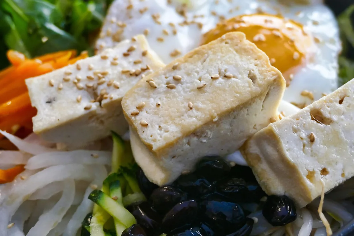 Kousky tofu se zeleninou a vejcem na talíři.