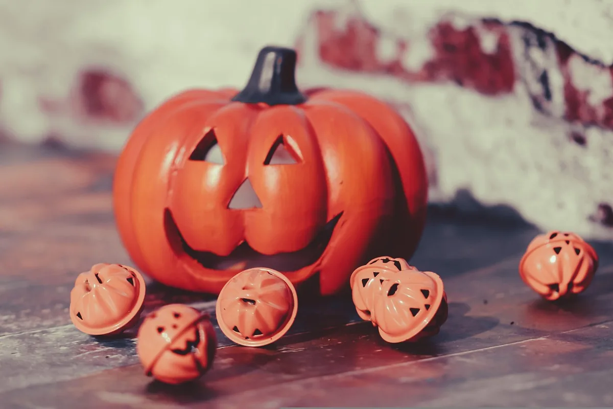 Oranžová halloweenská dýně a malé ozdoby ve tvaru dýní.