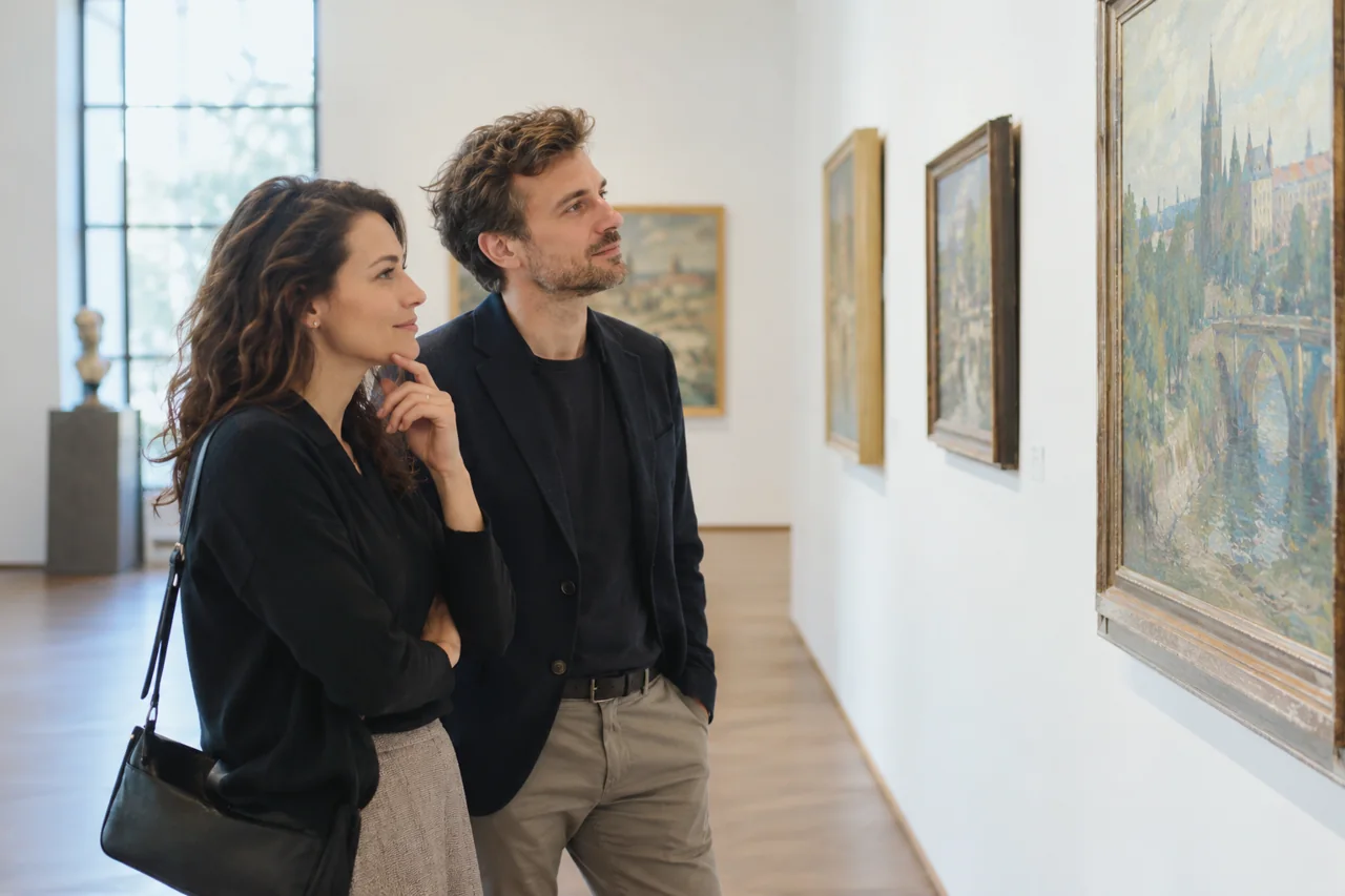 Dva dospělí prohlížejí obrazy v klidné galerii